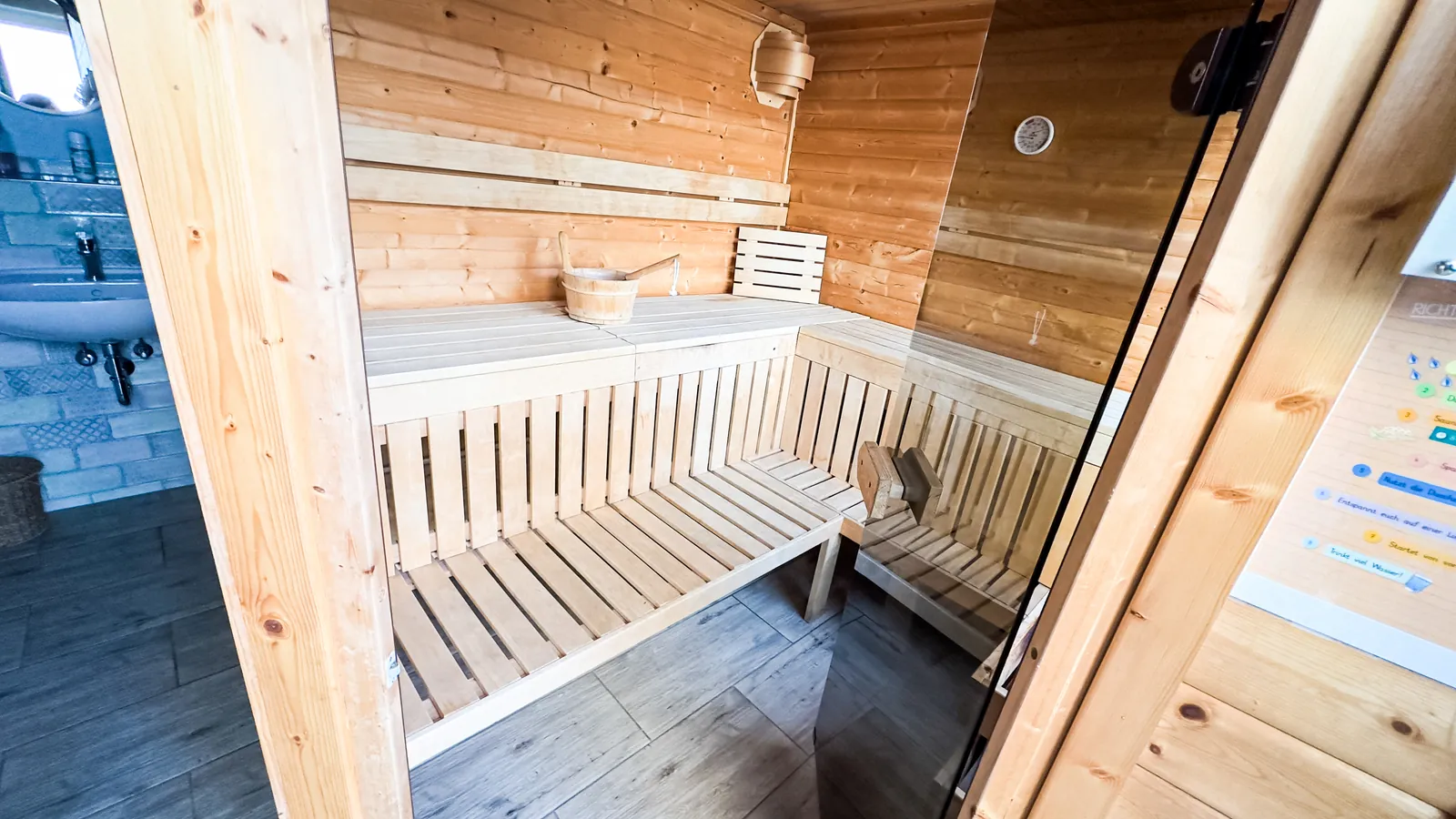 Finnische Sauna aus hellem Holz mit Saunakübel und Thermometer